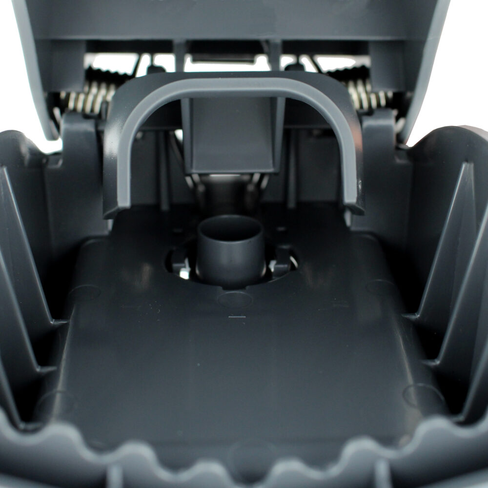 Inuti en grå fällstruktur med fjädrar och plastdetaljer.